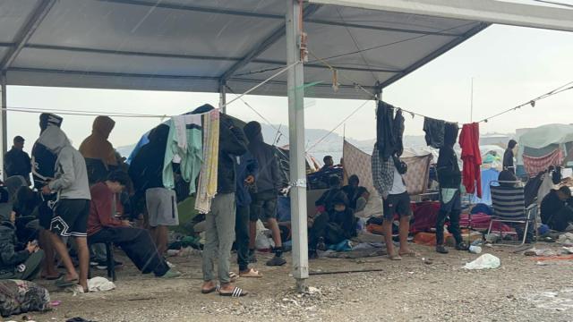 Varios migrantes esperan a ser trasladados en la explanada del Guano.