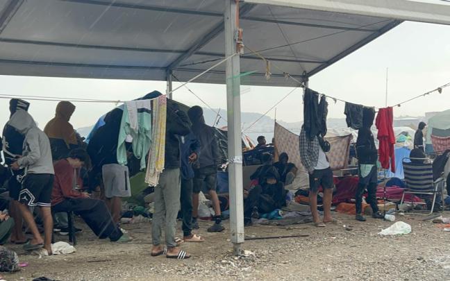 Varios migrantes esperan a ser trasladados en la explanada del Guano.