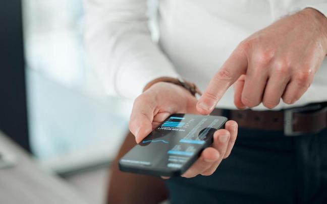 Una persona realiza con su móvil una operación en la aplicación de su banco.