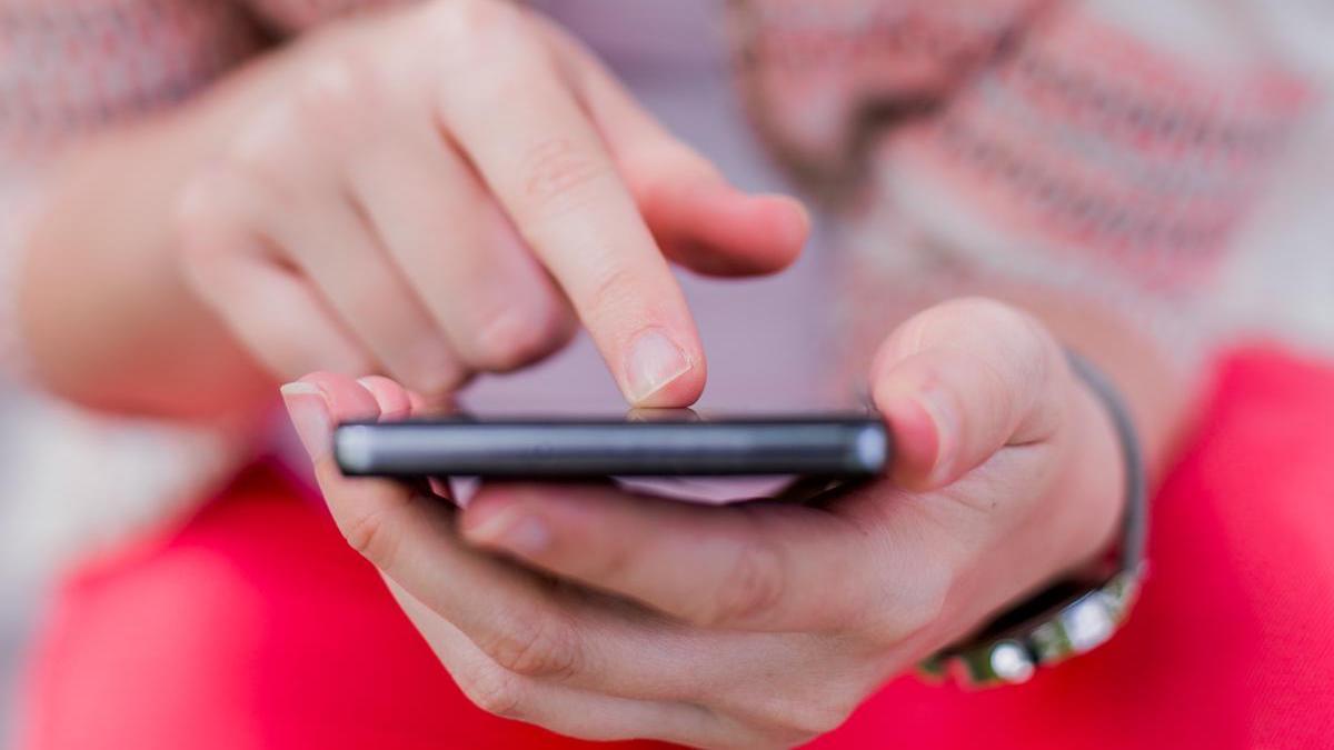 Una adolescente utiliza un teléfono móvil.
