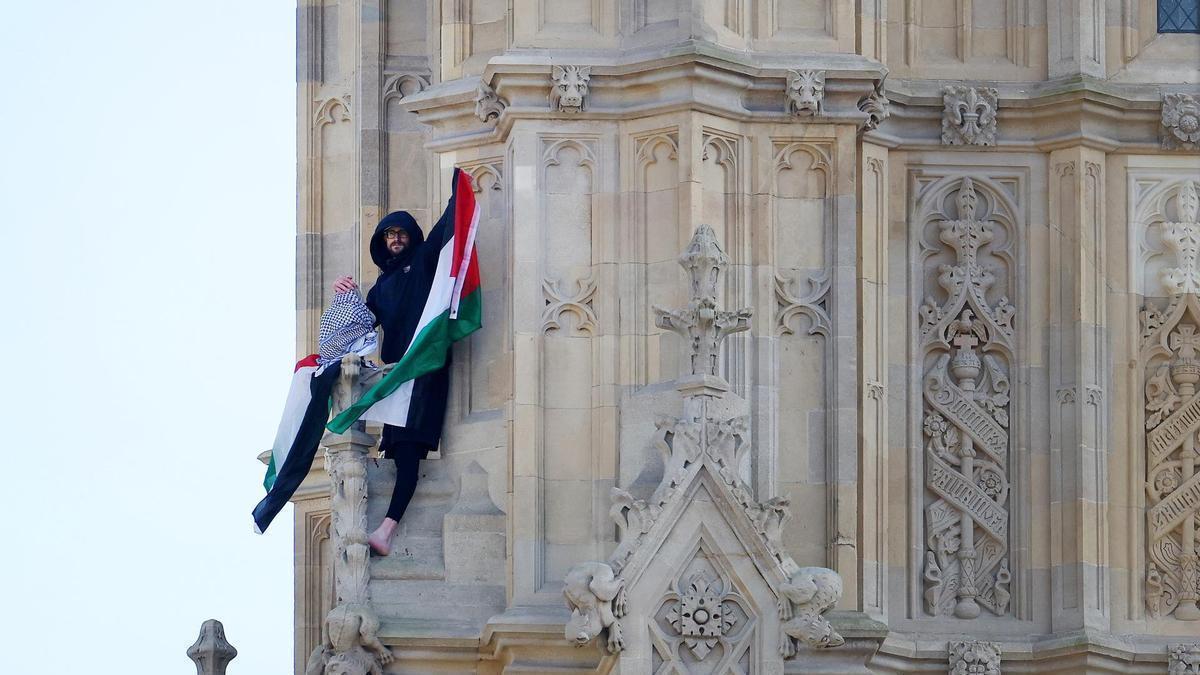 El activista propalestino alza la bandera de Palestina desde la torre Elizabeth, que alberga el Big Ben, del palacio de Westminster.