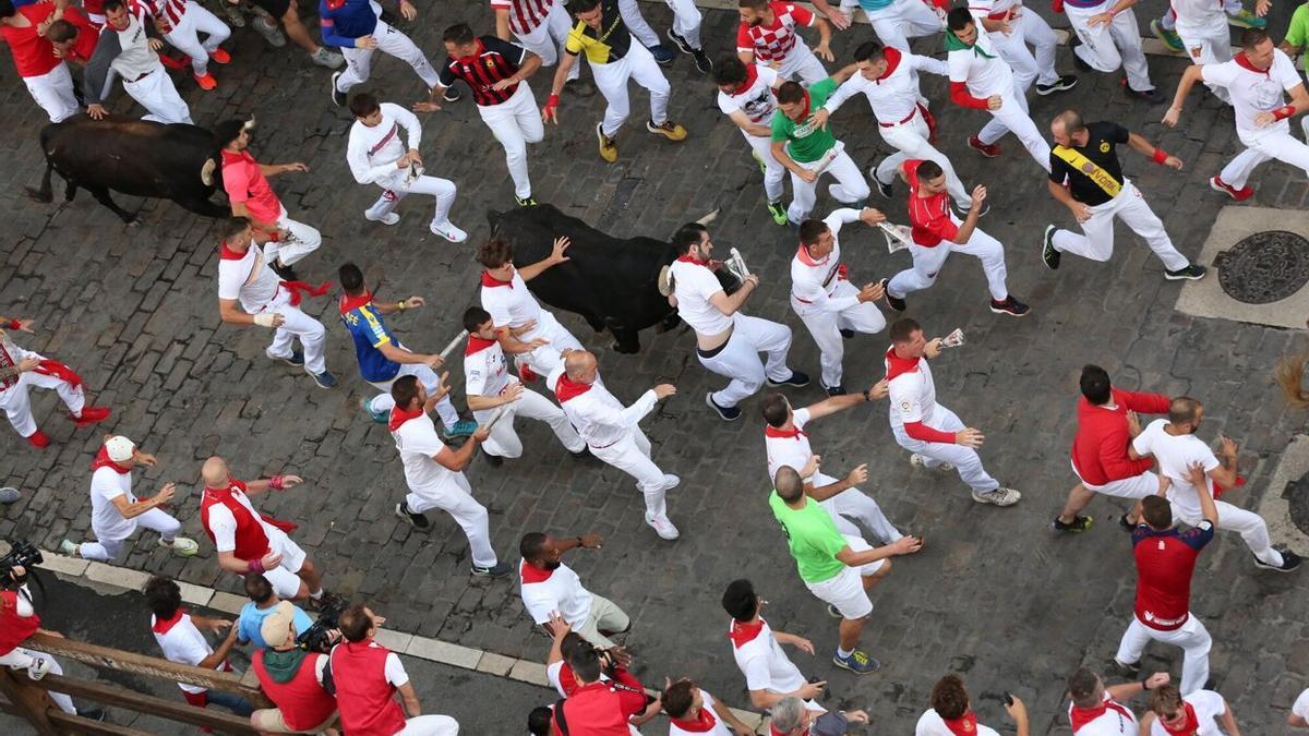 Imagen del sexto encierro de los Sanfermines, con un mozo delante del toro en Telefónica.