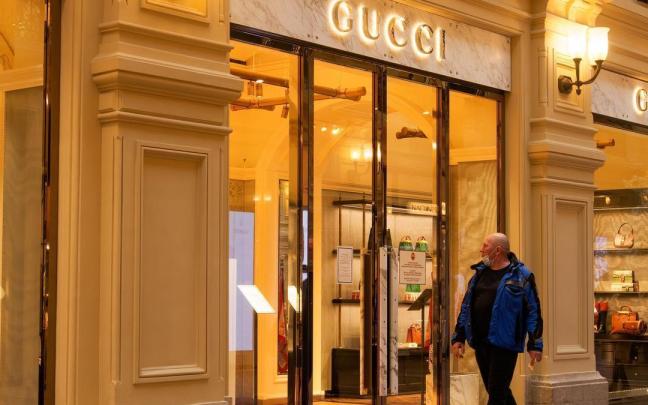 Un hombre pasea ante una tienda de Gucci cerrada.