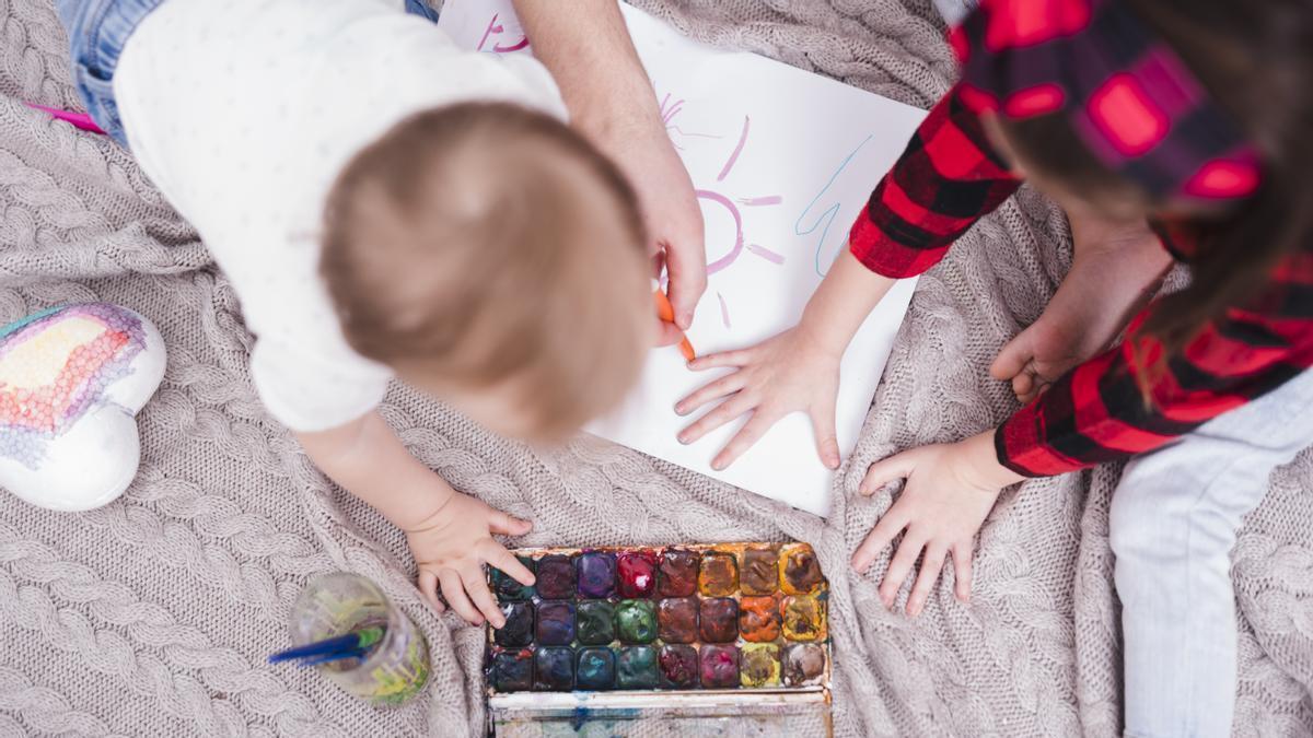 Niño pequeño dibujando con temperas y pinturas en el salón.