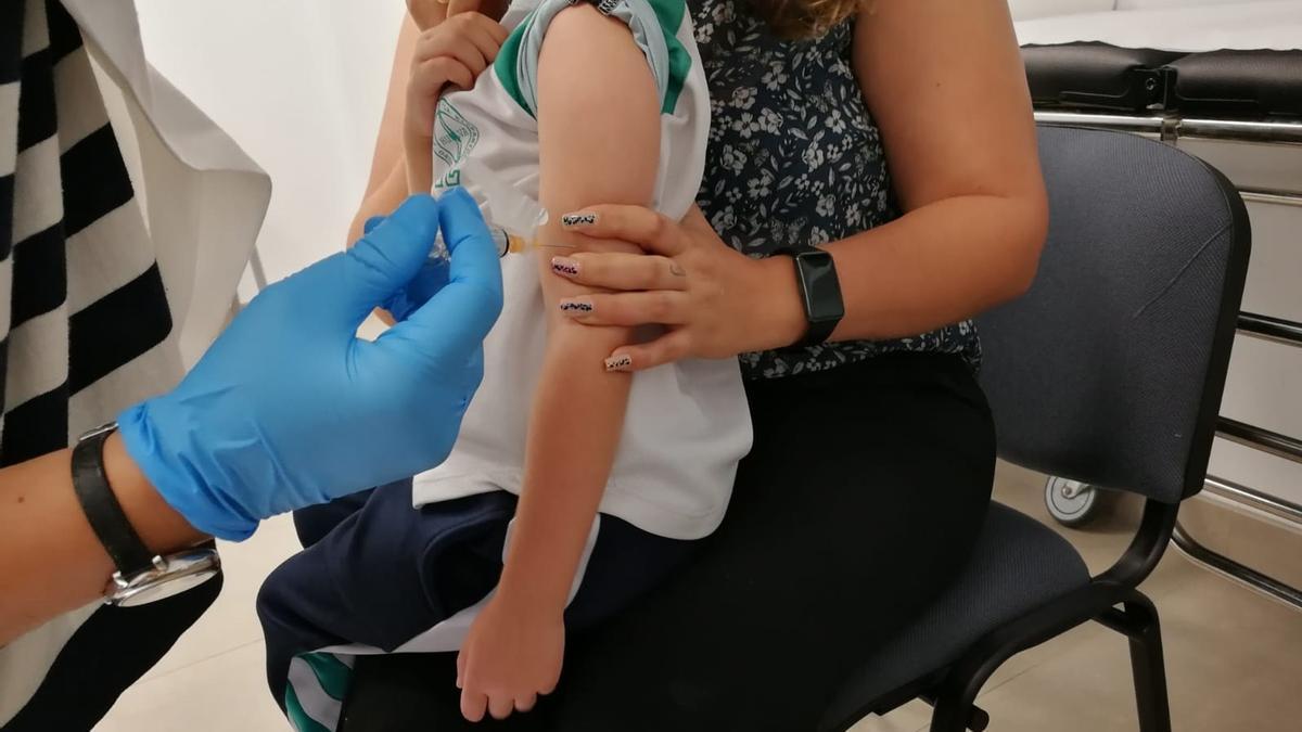 Una sanitaria administra a una niña la vacuna de la gripe.