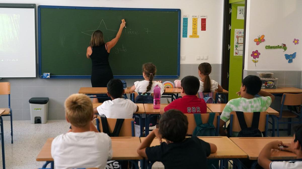 Una profesora escribe en la pizarra en el inicio del curso escolar.