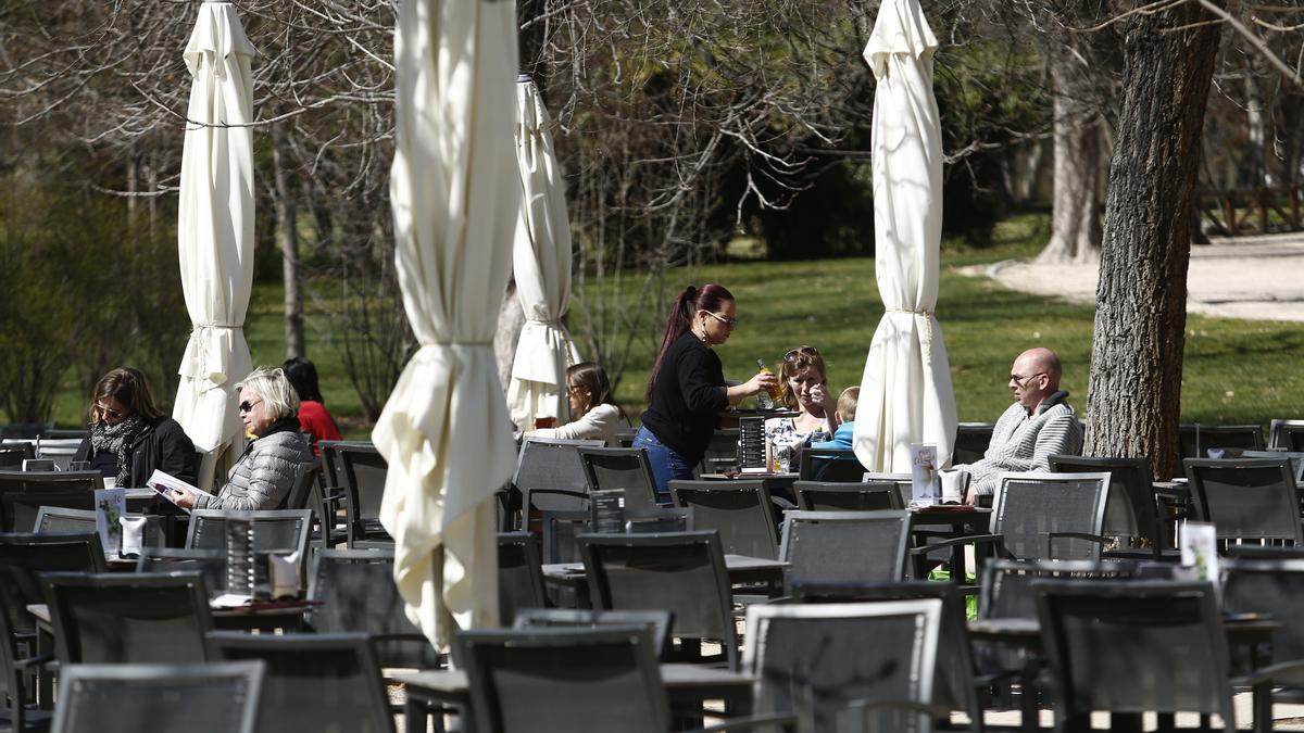 Una camarera sirve mesas en una terraza al sol.