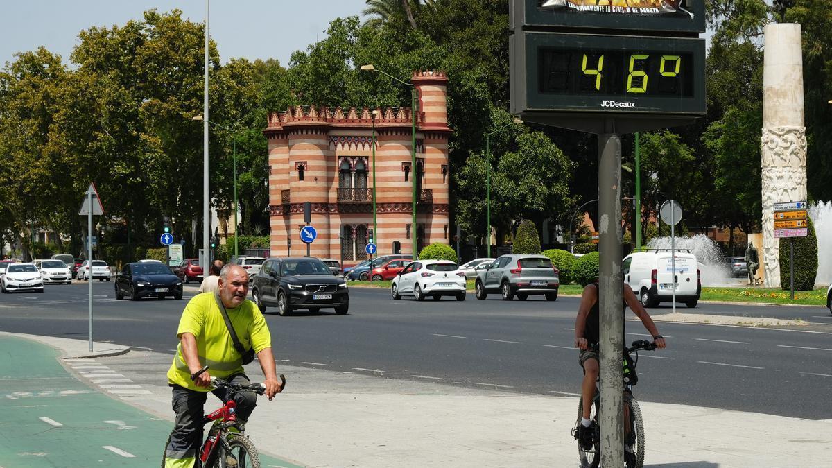 Un hombre circula en bicicleta por Sevilla junto a un termómetro que marca 46 grados.