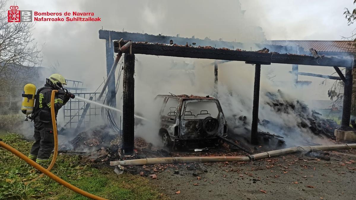 Un bombero trabaja en la extinción del incendio de la leñera que alcanzó a un vehículo