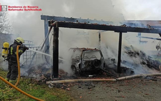 Un bombero trabaja en la extinci&oacute;n del incendio de la le&ntilde;era que alcanz&oacute; a un veh&iacute;culo