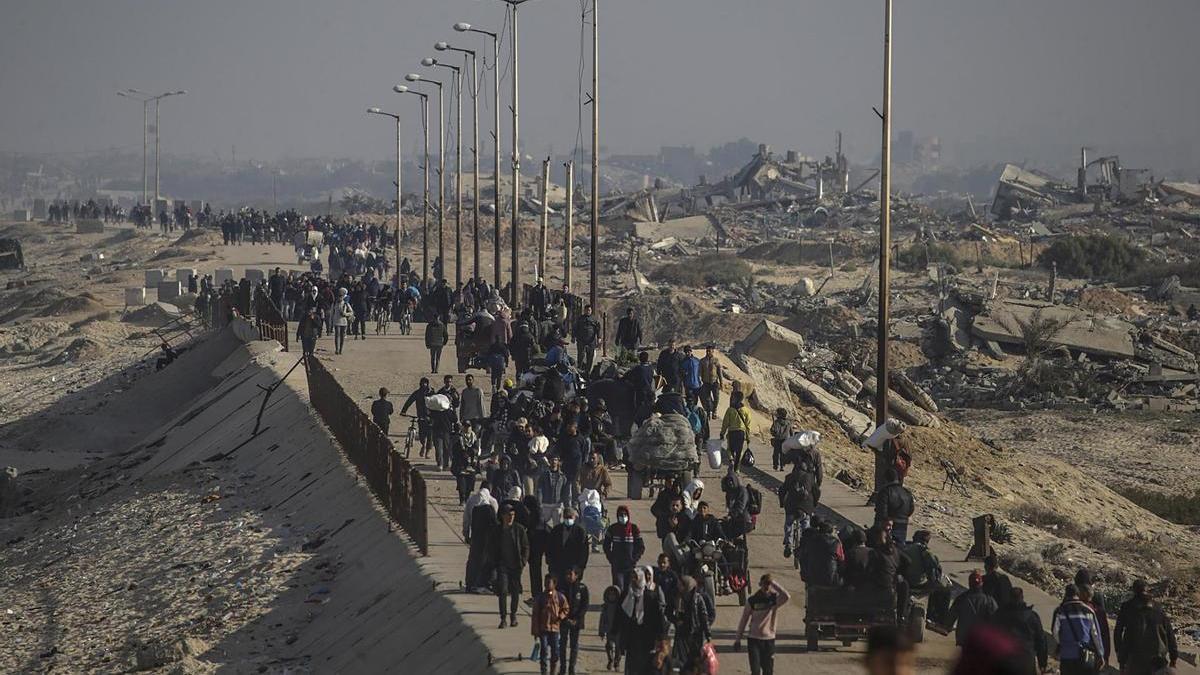 Desplazados palestinos caminan entre los escombros de la ciudad de Gaza.