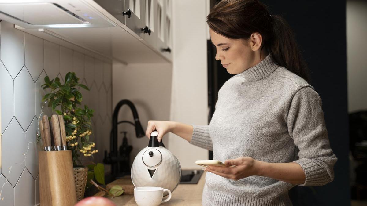 Mujer se sirve el café recién hecho en la cafetera en una taza