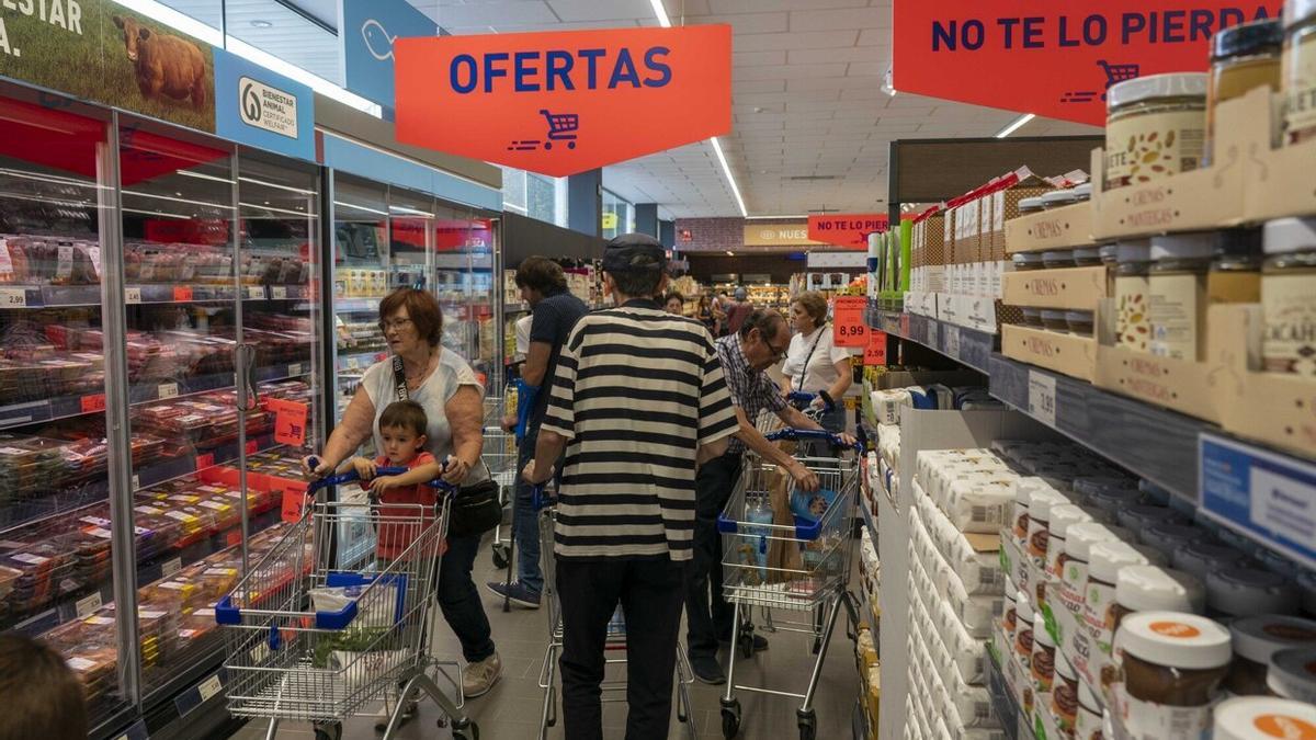Unas personas, haciendo la compra en un supermercado.