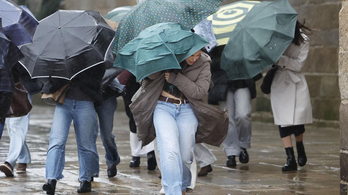 Una mujer se cubre con un paraguas del fuerte viento.