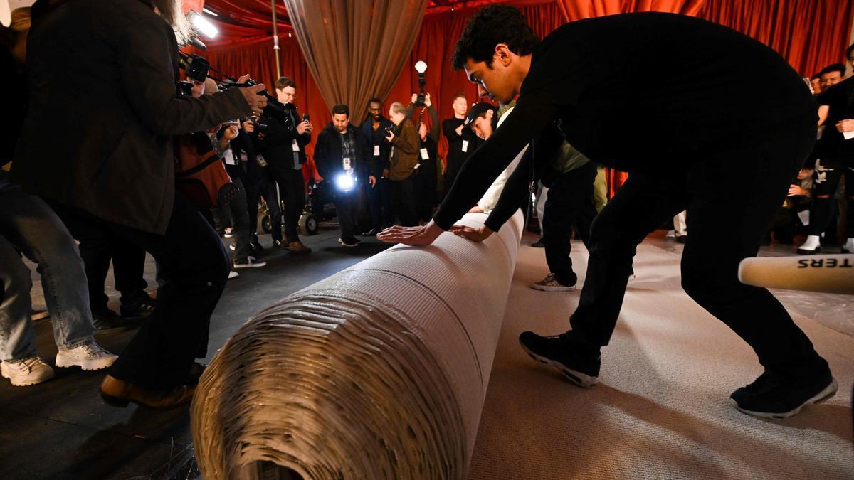 Operarios despliegan la nueva alfombra champán de los Oscars.