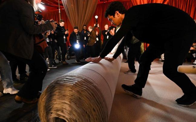 Operarios despliegan la nueva alfombra champán de los Oscars.
