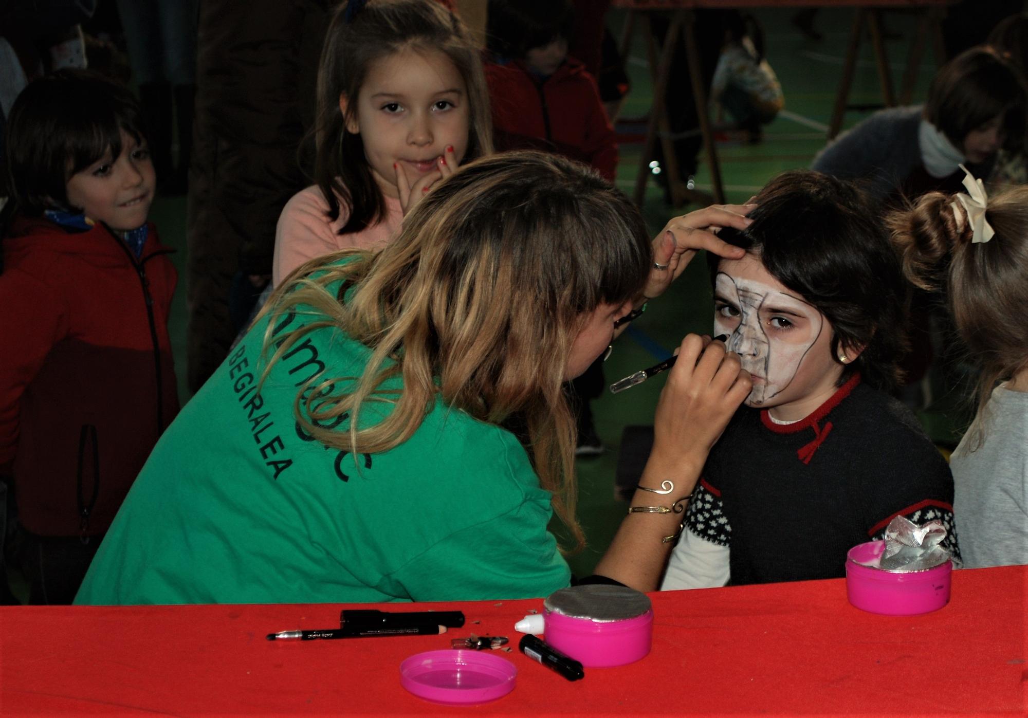 Una monitora de tiempo libre maquillando a una niña en un parque infantil en Amurrio