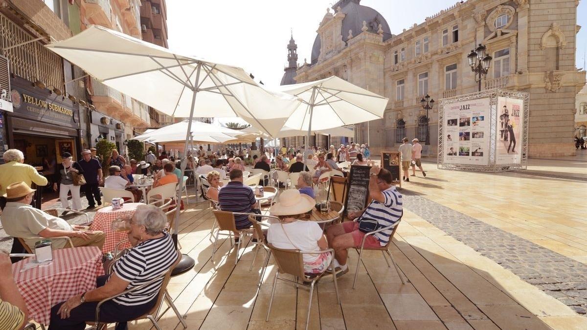 Varias personas toman algo en una terraza en verano.