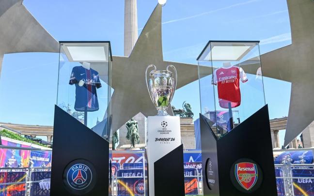 Imagen de las camisetas del Paris Saint-Germain y del Arsenal, junto el trofeo de la Champions League.