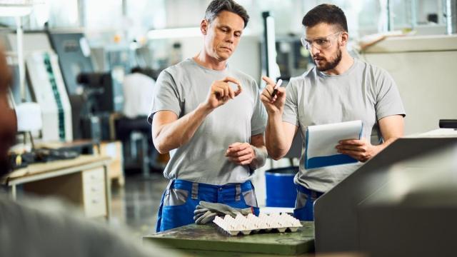 Dos trabajadores desempeñan su labor en una fábrica. Dos trabajadores desempeñan su labor en una fábrica.
