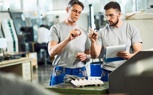 Dos trabajadores desempeñan su labor en una fábrica.