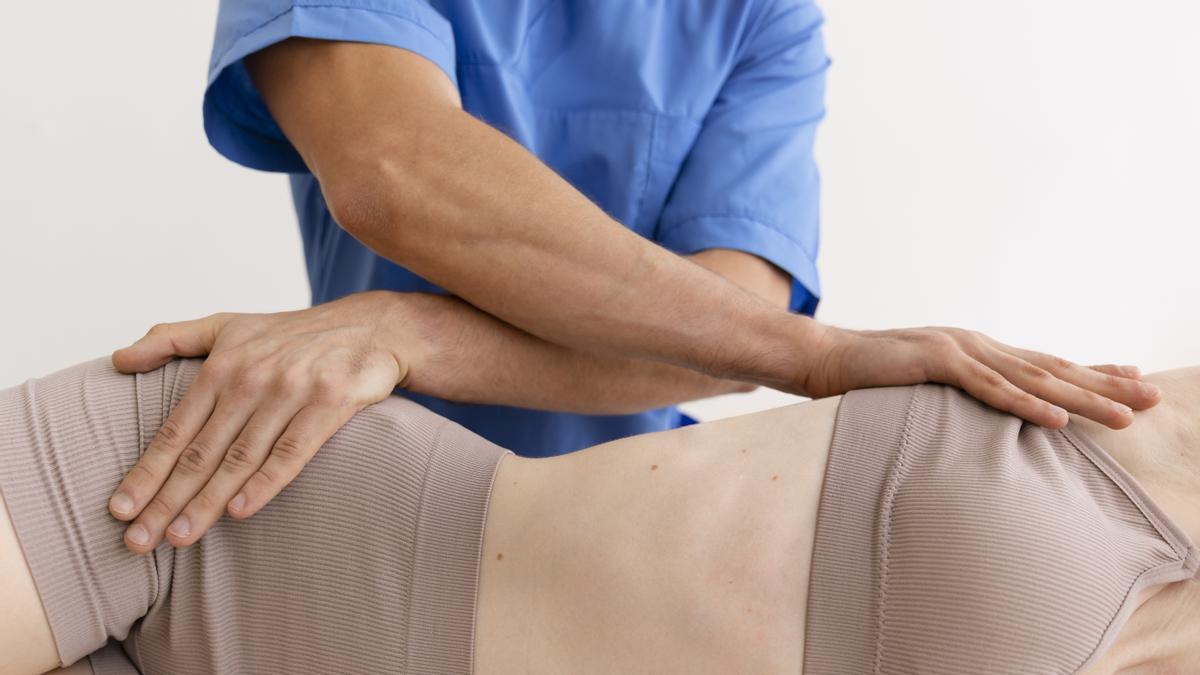 Un fisioterapeuta atiende a una mujer postrada en la cama.