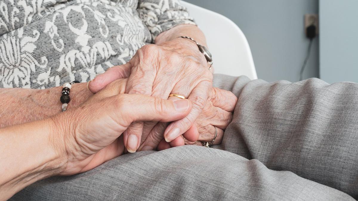 Dos personas mayores entrelanzan sus manos.