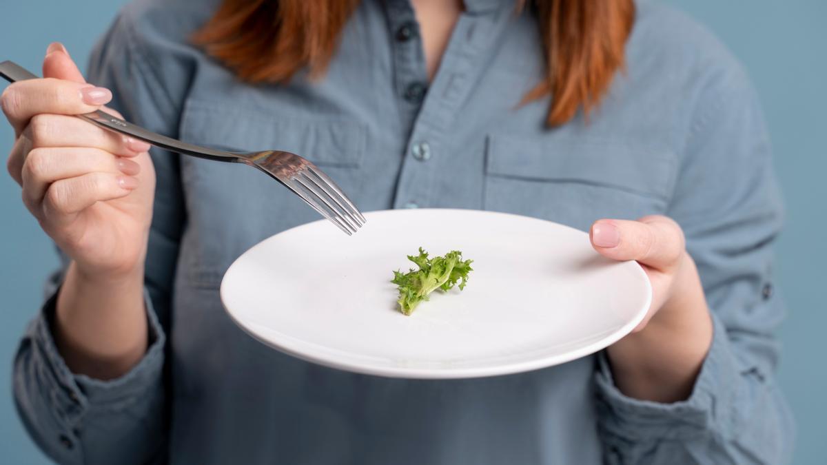 Una mujer sujeta un plato con una pequeña hoja de escarola.