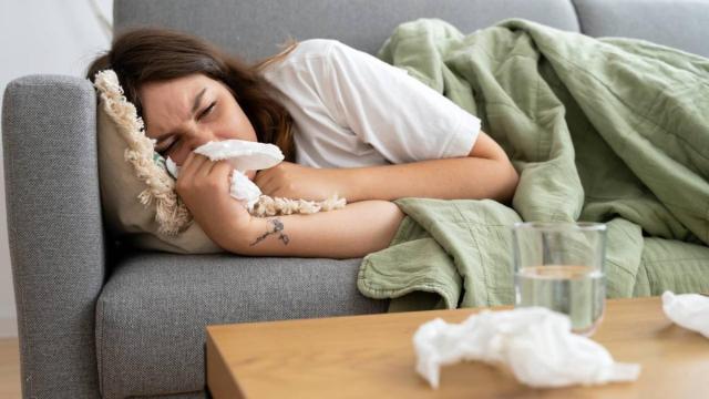 Una mujer, rodeada de pañuelos en un sofá.