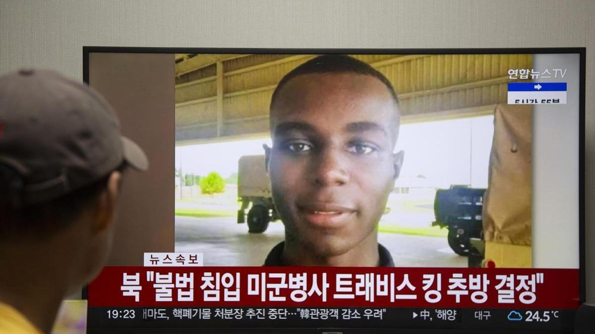 Un hombre observa una imagen de Travis King en la televisión norcoreana.