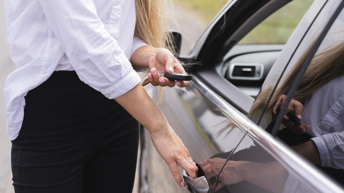 Chica abre el coche con el mando mientras agarra la manilla para acceder al interior