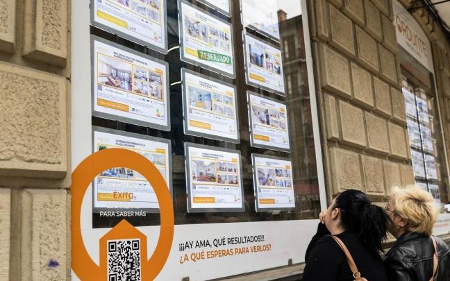 Dos mujeres miran viviendas en venta en una inmobiliaria.