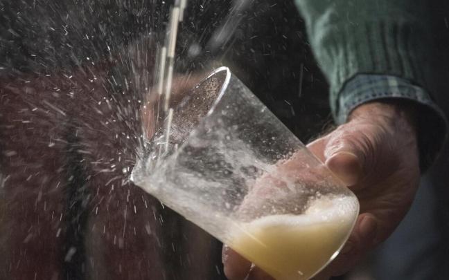 Una persona hace 'txotx' en una sidrería Una persona hace 'txotx' en una sidrería