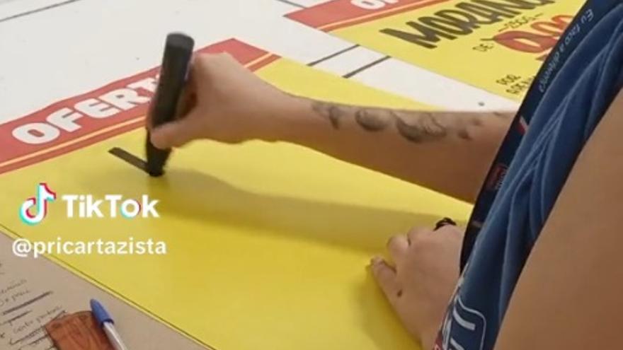 La mujer, comenzando a escribir un cartel del supermercado.