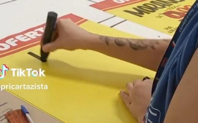 La mujer, comenzando a escribir un cartel del supermercado.