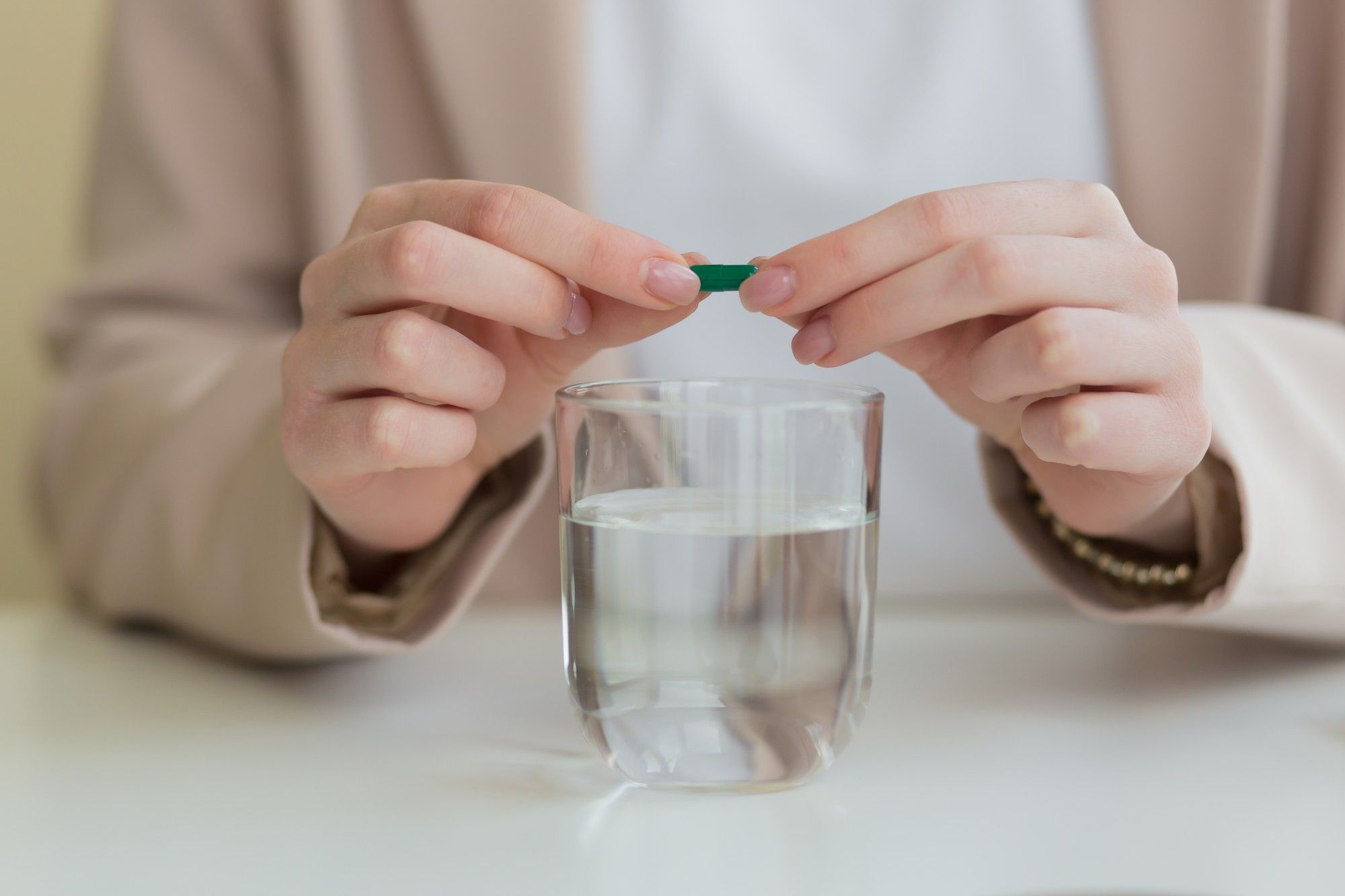 Una mujer abre una cápsula para diluir su contenido en agua.