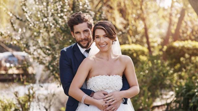 Una pareja de novios posa al aire libre en el día de su boda.