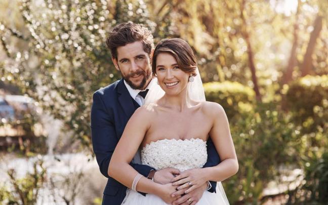 Una pareja de novios posa al aire libre en el día de su boda.