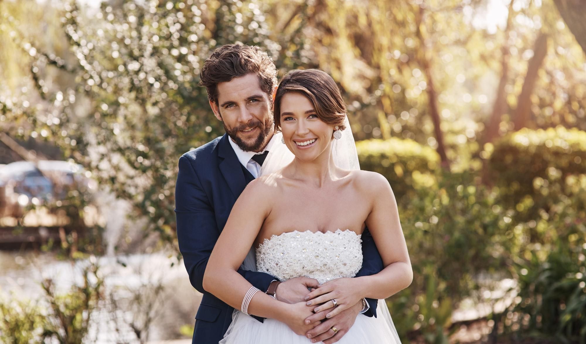 Una pareja de novios posa al aire libre en el día de su boda.