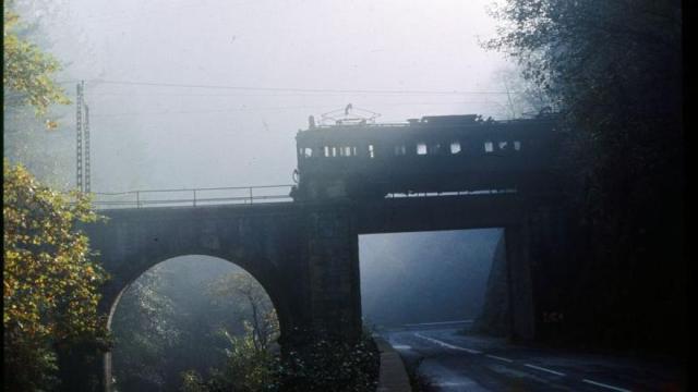 El tren del Urola sale de un túnel para atravesar un puente, sobre la carretera Urretxu-Azkoitia.