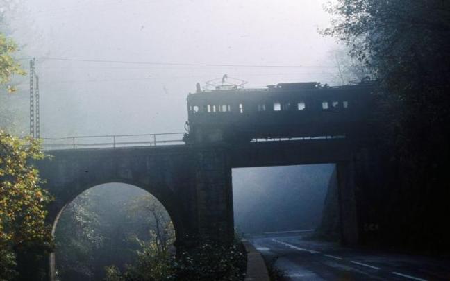 El tren del Urola sale de un túnel para atravesar un puente, sobre la carretera Urretxu-Azkoitia.