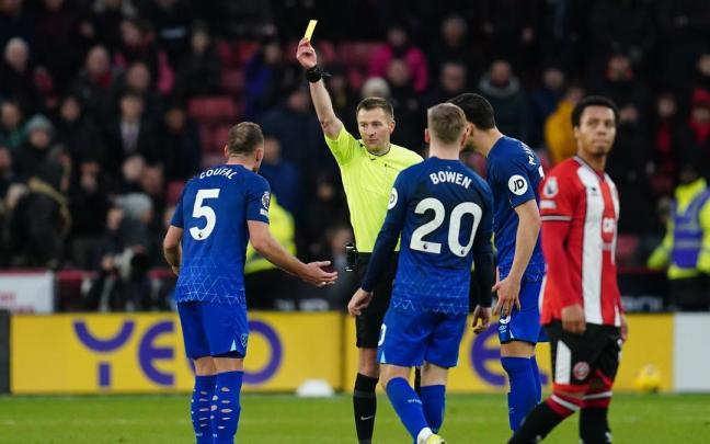 Un árbitro saca una tarjeta amarilla a un jugador en un partido de la Premier.
