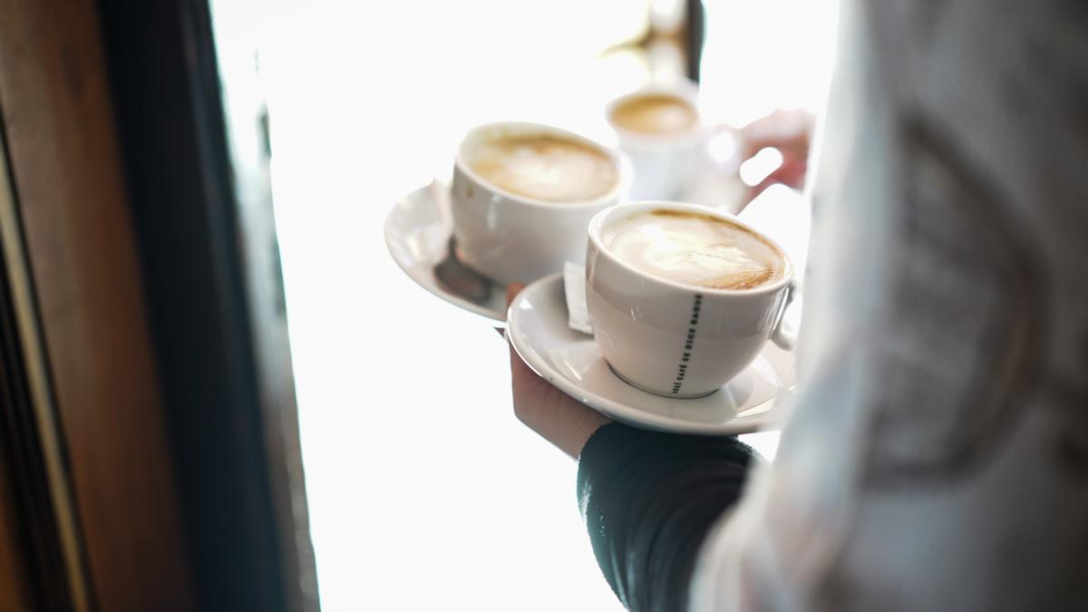 Un camarero sirve varios cafés en una cafetería