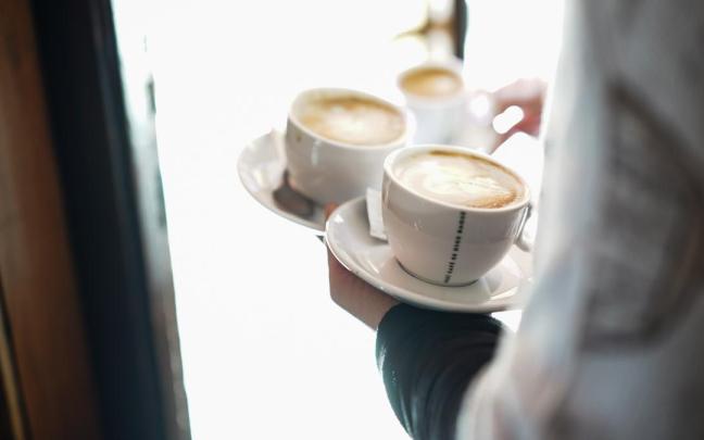 Un camarero sirve varios cafés en una cafetería
