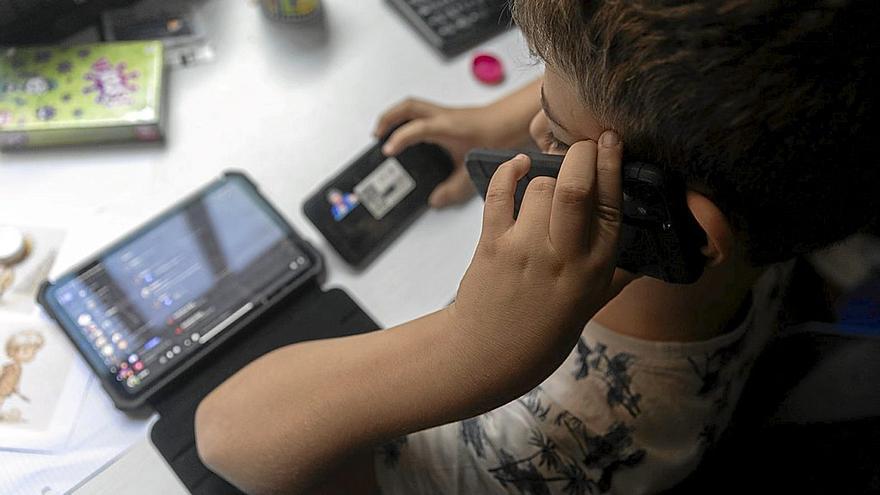 Un niño utilizando dos teléfonos móviles y una tablet. | FOTO: EP