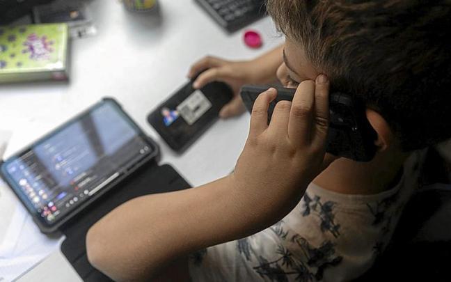 Un niño utilizando dos teléfonos móviles y una tablet. | FOTO: EP