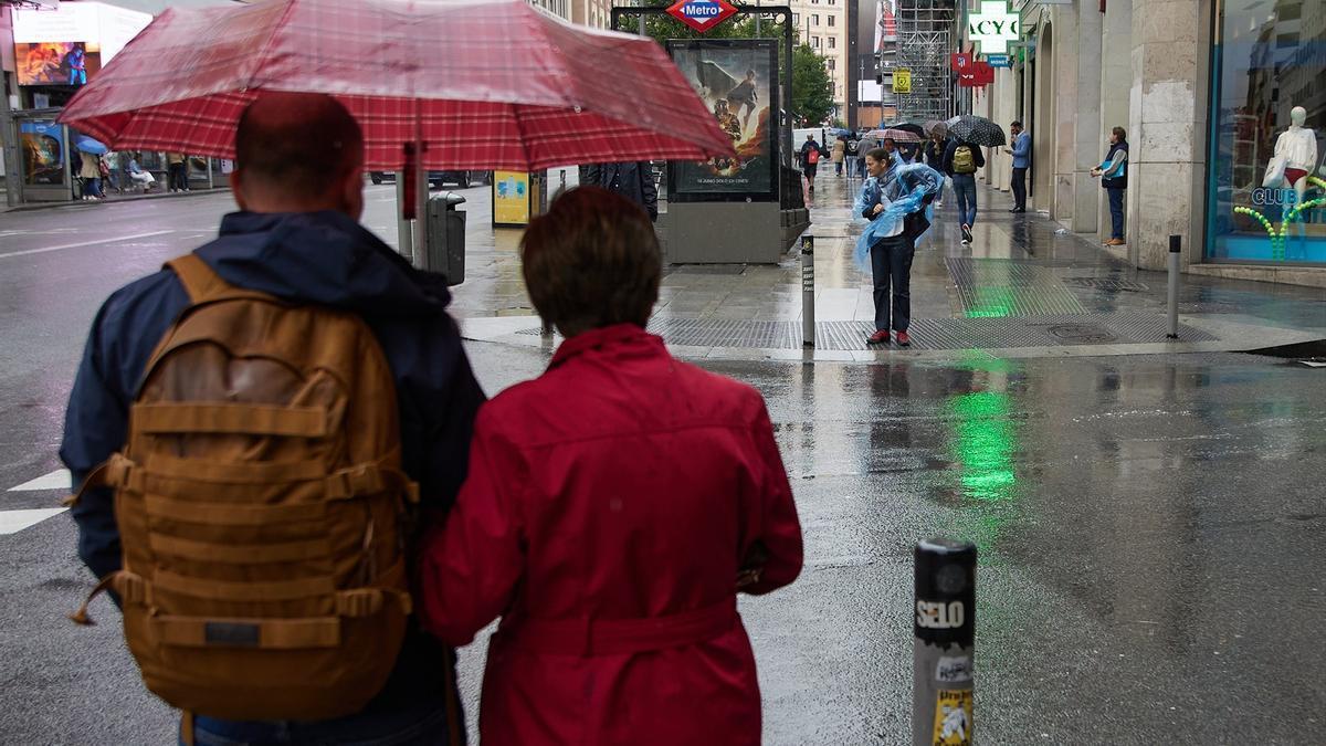 Dos personas con paraguas caminan bajo la lluvia.