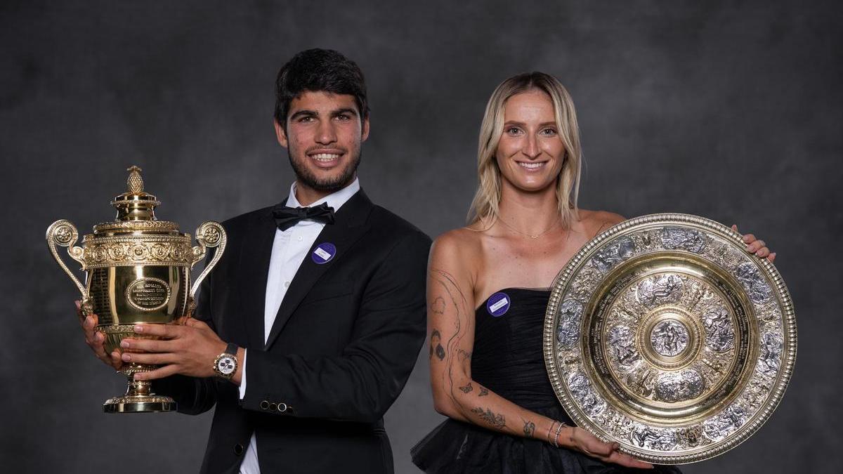 Alcaraz y la checa Marketa Vondrousova posan con sus trofeos de campeones de Wimbledon.