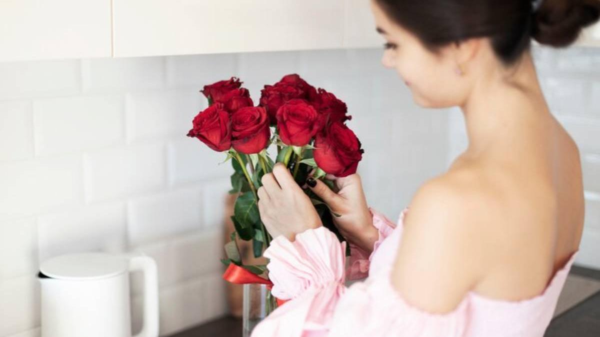 Mujer coloca un ramo de rosas en un jarrón con agua.