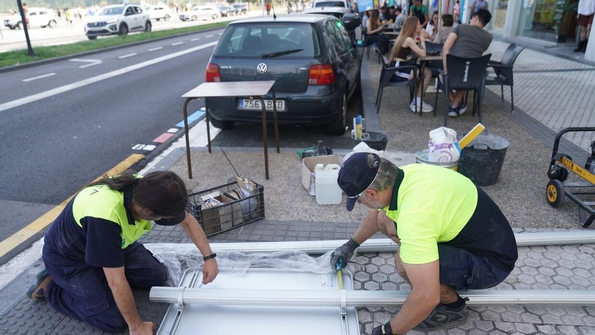 Operarios de la OTA preparan un cartel con las nuevas medidas en la avenida de la Zurriola